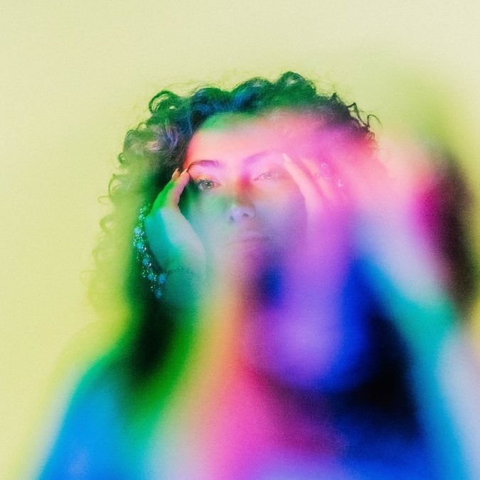 a man with a multicolored shirt covering his face
